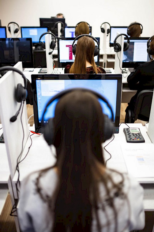 Obraz przedstawia osoby pracujące przed komputerami