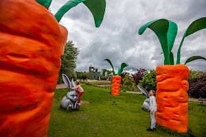 Pole ogromnych marchewek i dwójka bawiących się dzieci