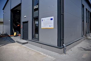budynek firmy, wejście na halę produkcyjną, na ścianie budynku tablica informacyjna dotycząca projektu