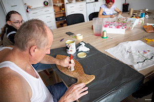 Leworęczny mężczyzna pokrywa lakierem wyciętą z drewna figurę ryby